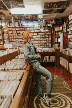 a woman sitting on top of a wooden bench next to a record store filled with records