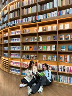 two women sitting on the floor in front of bookshelves