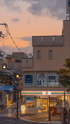 a city street at dusk with people walking on the sidewalk and buildings in the background