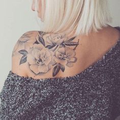 the back of a woman's shoulder with flowers tattooed on her left arm and chest