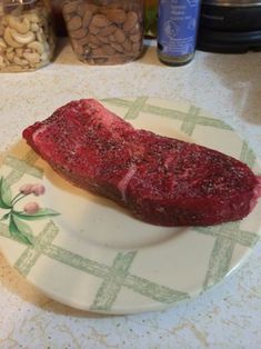 a piece of steak on a plate next to nuts