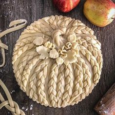 an apple pie sitting on top of a wooden table next to some doughnuts