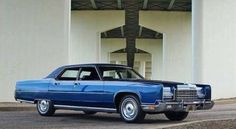 an old blue car is parked in front of a large white building with columns on it