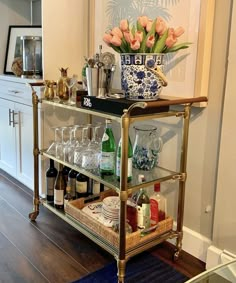 a bar cart filled with lots of bottles and glasses on top of a hard wood floor