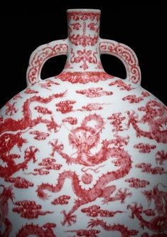 a red and white vase sitting on top of a table