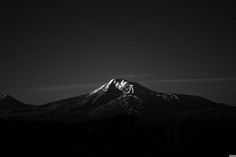 a black and white photo of the top of a mountain in the night sky with clouds