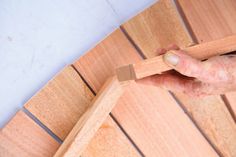 a person holding a piece of wood on top of a wooden flooring planks