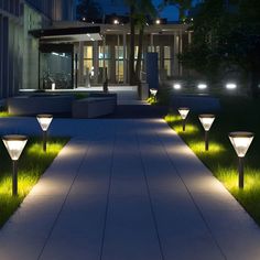 some lights that are on the side of a walkway in front of a building at night