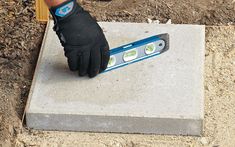 a pair of gloves on top of a cement block with a ruler in the middle