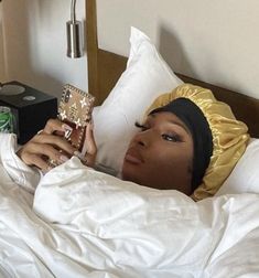 a woman laying in bed holding a cell phone