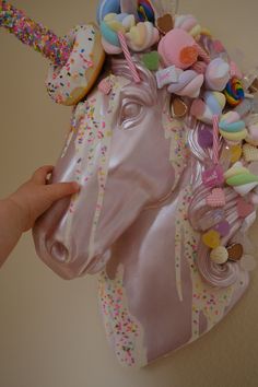 a pink unicorn head with sprinkles and candies on it