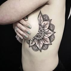 a woman's stomach with a flower tattoo on her left side ribcage