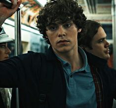 the young man is holding his cell phone up to his ear as he rides on the subway