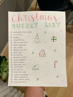 a hand holding up a christmas bucket list