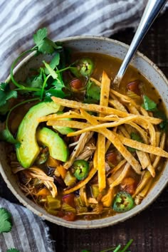 a bowl of chicken tortilla soup with avocado and cilantro