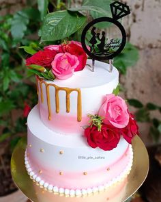 a three tiered cake with pink and red flowers on top is sitting on a gold plate