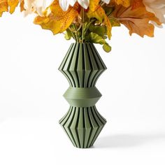 a green vase filled with white and yellow flowers