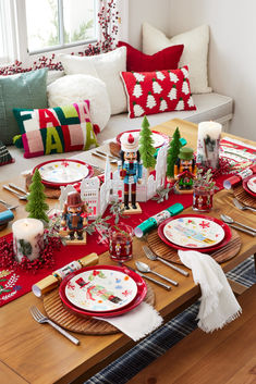 the table is set for christmas dinner with red and white plates, napkins, silverware