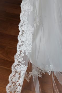 the back of a wedding dress with white lace on it's neck and veil