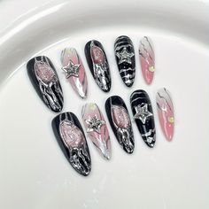 six different nail designs on a white plate with pink and black accents, all decorated with silver stars