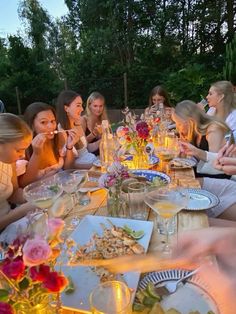 a group of people sitting around a table with food and drinks in front of them