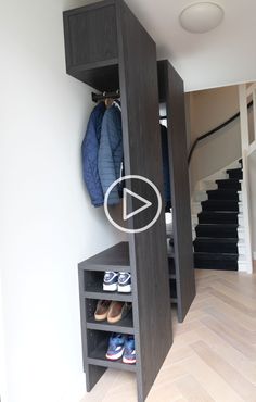 an open closet with shoes and coats hanging on the wall next to stairs in a house