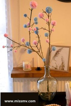 a vase filled with pink and blue flowers on top of a table next to candles