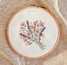 a close up of a embroidery on a piece of cloth with flowers in the middle