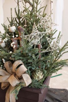 a small christmas tree in a pot with a bow on the top and other decorations around it