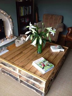 a coffee table made out of pallet wood with magazines on top and flowers in a vase