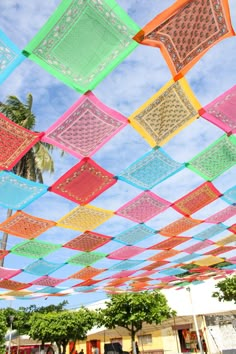 many colorful squares are hanging from the ceiling in front of a building with palm trees