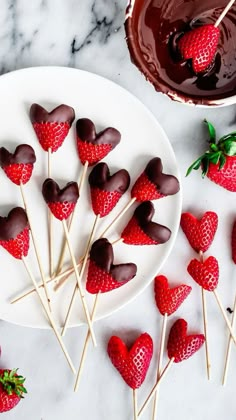 chocolate covered strawberries are arranged on skewers next to a bowl of melted chocolate