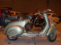 a green scooter parked in a garage next to other vehicles