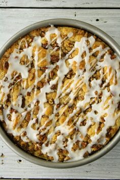 a pie with white icing and nuts in a pan on top of a wooden table