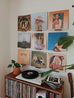 a record player sitting on top of a wooden shelf next to a wall filled with records