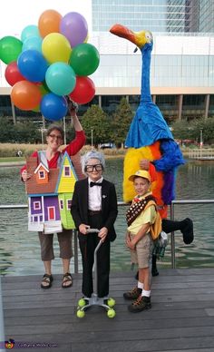 three people standing on a dock with balloons in the shape of animals and birds,