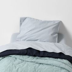 an unmade bed with blue and white sheets