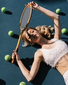 a woman is laying on the ground holding a tennis racket