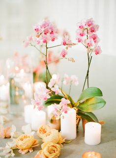 pink flowers and candles are on the table