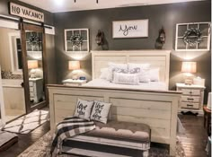 a white bed sitting inside of a bedroom on top of a hard wood floor next to two lamps