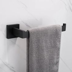 a towel hanging on the wall next to a black towel rack and white marble counter top