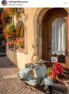 a scooter parked in front of a building with flowers on the windowsill