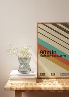 a vase filled with white flowers sitting on top of a wooden table next to a framed poster