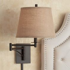 a lamp is mounted on the wall next to a white chair and headboard with buttons