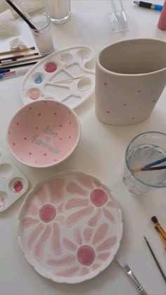 there are some paint brushes and bowls on the table with other things to draw in it