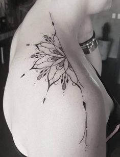 a black and white photo of a woman's shoulder with a flower tattoo on it