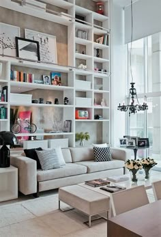 a living room filled with white furniture and lots of bookshelves on the wall