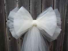 a white tulle bow hanging on a wooden fence