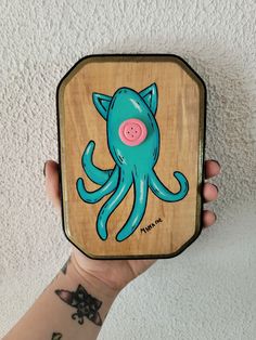 a person holding up a wooden box with an octopus on it