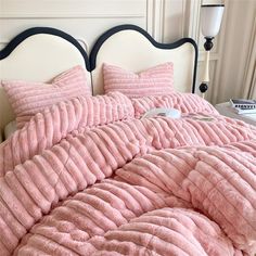 a bed with pink comforters and pillows on it